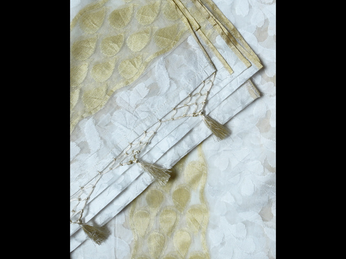 Off-white cotton saree featuring a subtle golden hue, adorned with black thread work and an abstract beaded design.