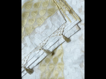 Off-white cotton saree featuring a subtle golden hue, adorned with black thread work and an abstract beaded design.